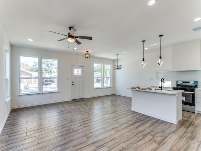 kitchen with light wood-style flooring, gas stove, open floor plan, and a sink