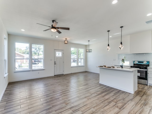 kitchen with stainless steel range, white cabinetry, plenty of natural light, and pendant lighting