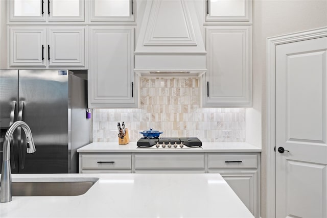 kitchen with white cabinets, stainless steel fridge, and custom exhaust hood