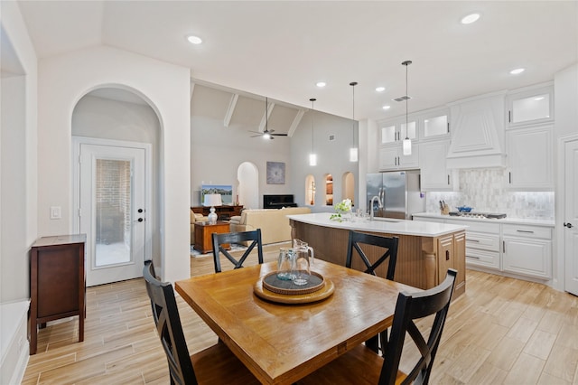 dining area featuring vaulted ceiling with beams, ceiling fan, light hardwood / wood-style flooring, and sink