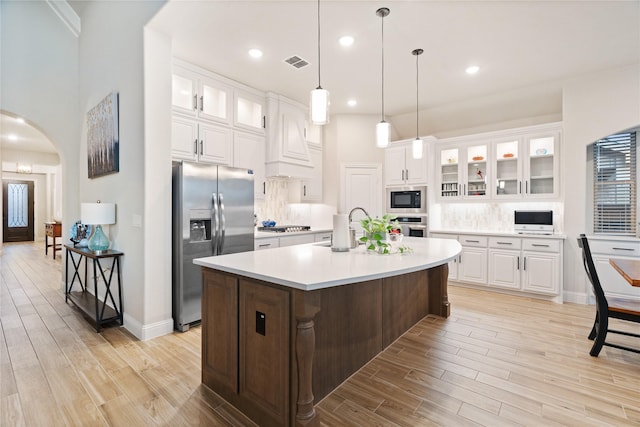 kitchen featuring white cabinetry, a kitchen island with sink, appliances with stainless steel finishes, and light hardwood / wood-style flooring