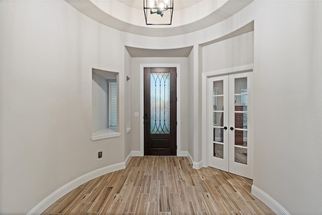 foyer entrance with an inviting chandelier, light wood-type flooring, and french doors