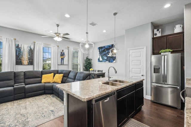 kitchen with dark hardwood / wood-style flooring, sink, appliances with stainless steel finishes, and an island with sink