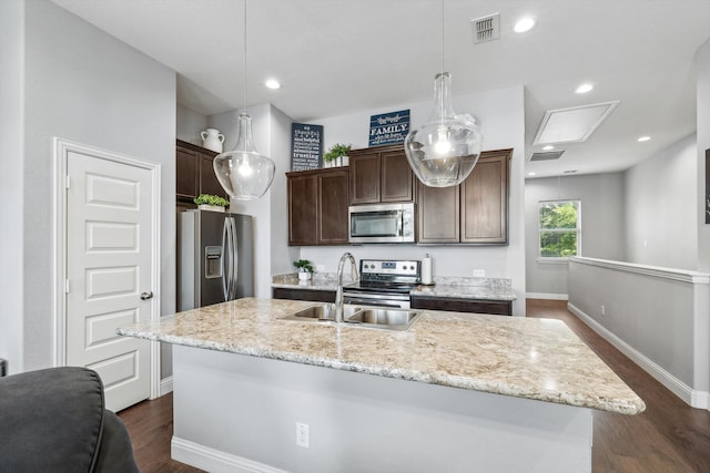 kitchen featuring stainless steel appliances, hanging light fixtures, sink, and an island with sink