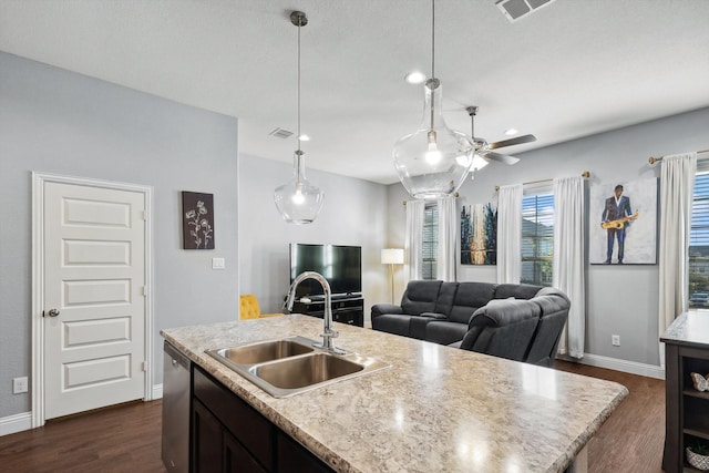 kitchen featuring stainless steel dishwasher, a center island with sink, sink, and hanging light fixtures