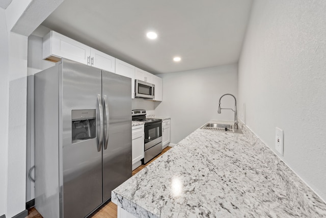 kitchen featuring light wood-type flooring, stainless steel appliances, sink, and white cabinets