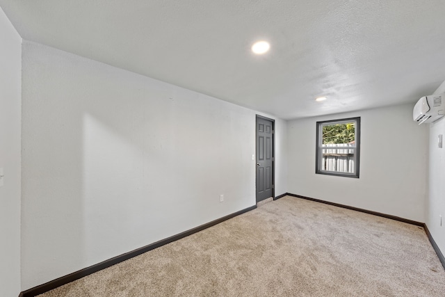 spare room with an AC wall unit, light colored carpet, and a textured ceiling