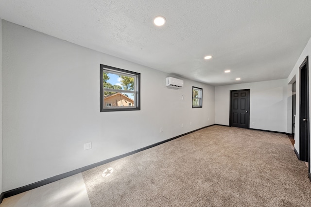 carpeted empty room featuring a wall unit AC and a textured ceiling