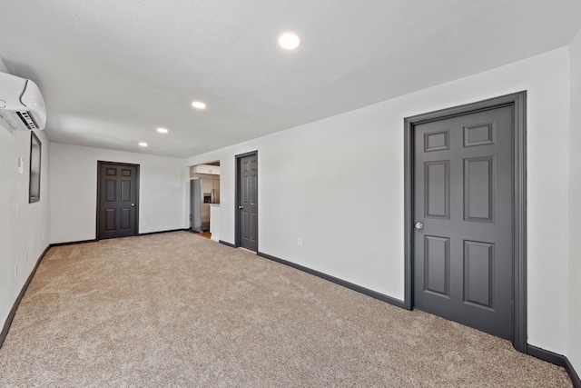 empty room featuring light carpet, a textured ceiling, and a wall unit AC