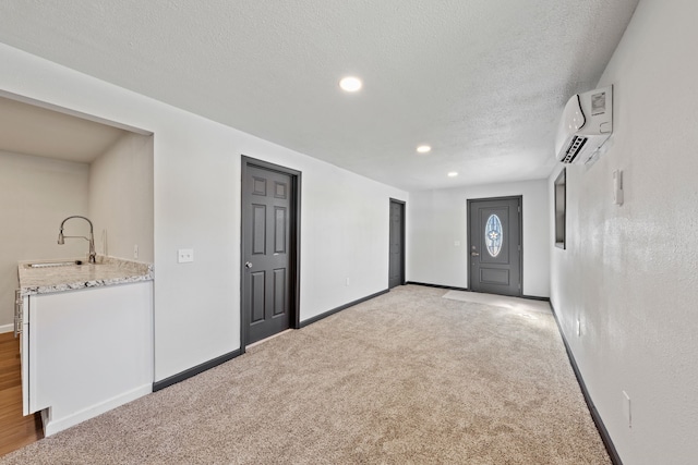 interior space featuring light carpet, sink, a textured ceiling, and a wall mounted AC