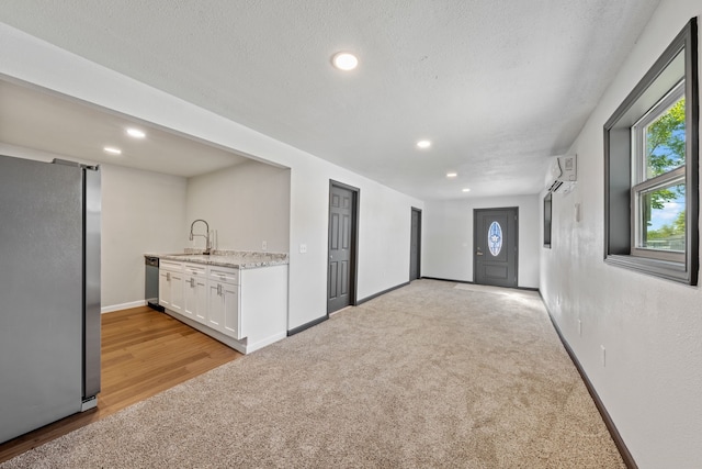 interior space featuring sink, a textured ceiling, stainless steel appliances, light stone countertops, and white cabinets