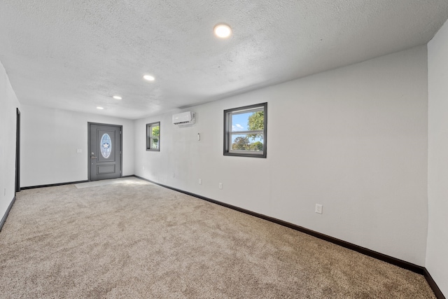 empty room featuring light carpet, a textured ceiling, and a wall mounted AC