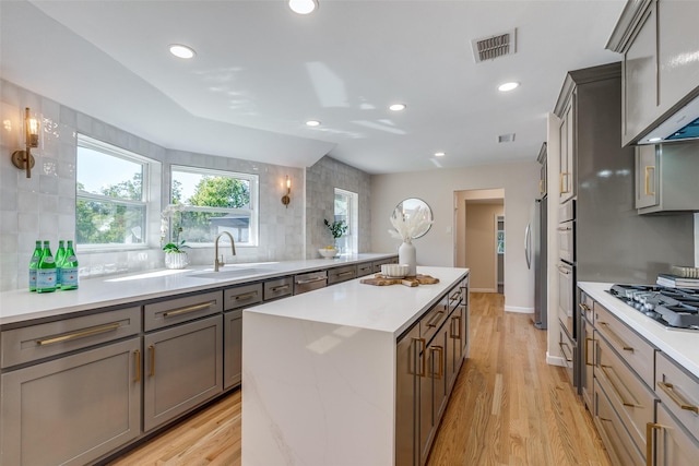 kitchen featuring decorative backsplash, visible vents, stainless steel appliances, a sink, and a center island