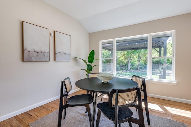 dining space featuring plenty of natural light, baseboards, lofted ceiling, and wood finished floors