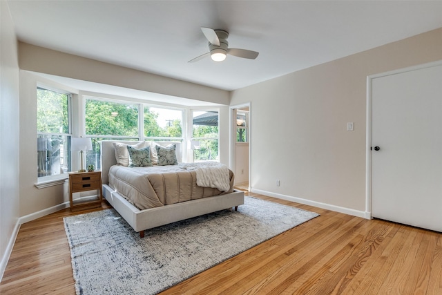 bedroom with light wood finished floors, baseboards, and a ceiling fan