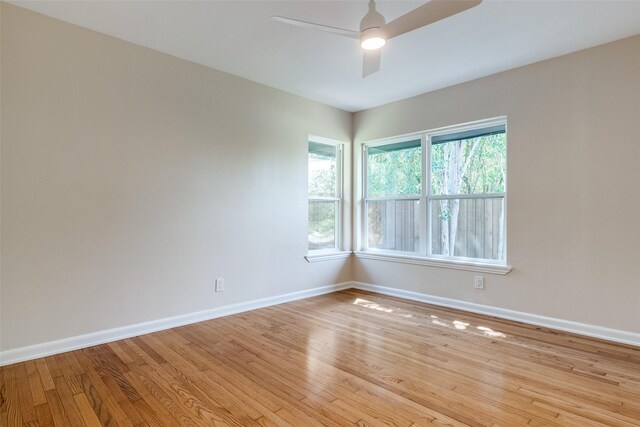 empty room featuring baseboards, ceiling fan, and light wood finished floors