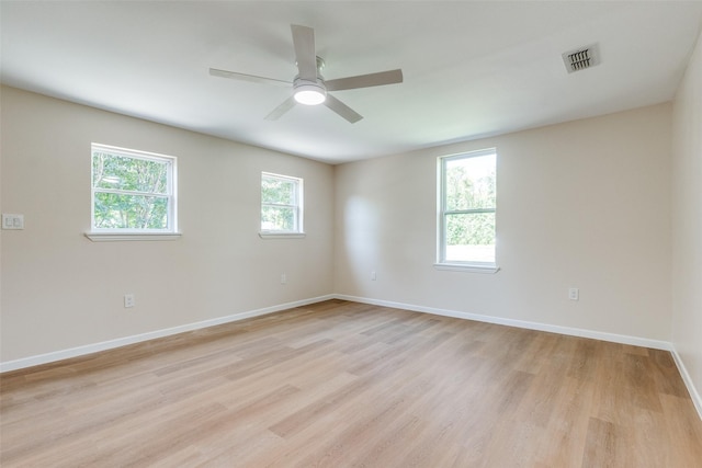 spare room featuring baseboards, visible vents, light wood-style flooring, and ceiling fan