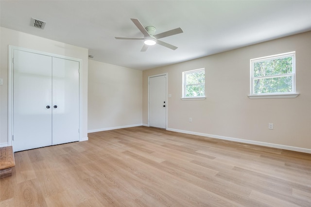 spare room featuring light wood-type flooring, a ceiling fan, baseboards, and visible vents