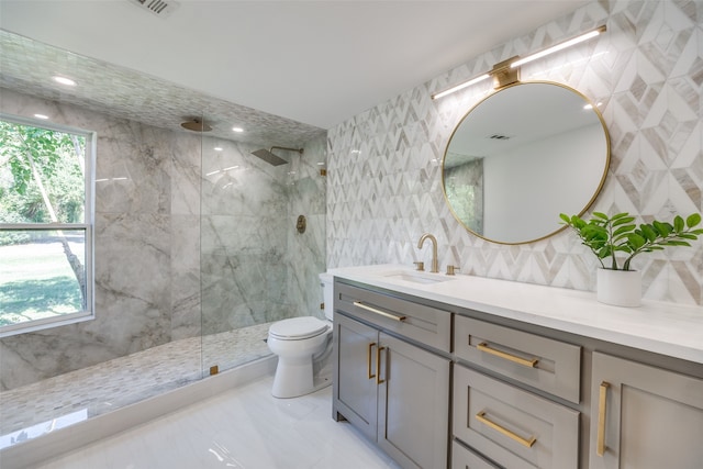 bathroom featuring a wealth of natural light, vanity, a tile shower, and toilet