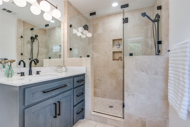 bathroom with vanity, a tile shower, and tile patterned flooring