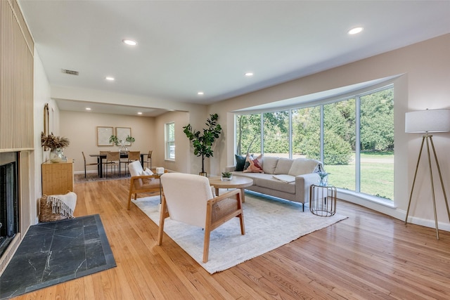 living room with light wood finished floors, a fireplace, baseboards, visible vents, and recessed lighting
