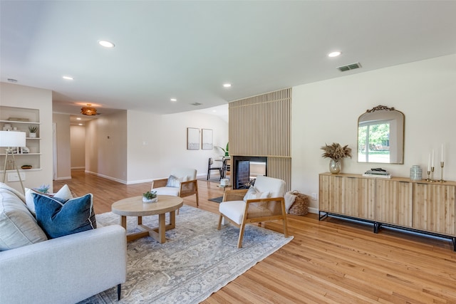 living room featuring a fireplace, light wood-type flooring, and built in shelves