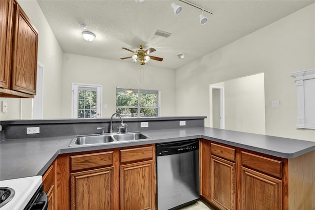 kitchen with kitchen peninsula, sink, rail lighting, appliances with stainless steel finishes, and a textured ceiling