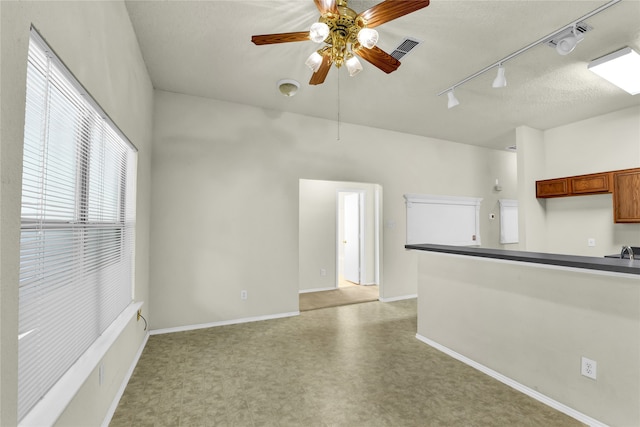 unfurnished living room featuring a textured ceiling, ceiling fan, and rail lighting