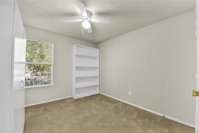 empty room featuring a textured ceiling, light colored carpet, and ceiling fan