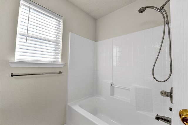 bathroom featuring a textured ceiling and tiled shower / bath