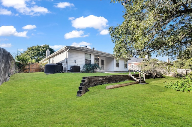 rear view of house with a yard and central AC unit