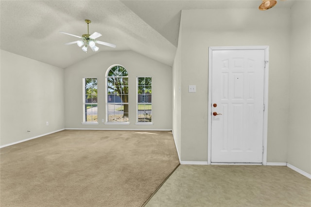 carpeted entrance foyer with lofted ceiling, a textured ceiling, and ceiling fan