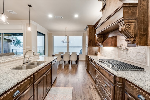 kitchen with light stone countertops, sink, hanging light fixtures, and dark hardwood / wood-style flooring