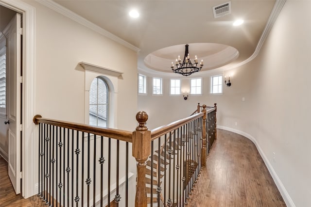 corridor with crown molding, a chandelier, a raised ceiling, and dark hardwood / wood-style flooring