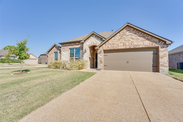 view of front of property with a front yard, central AC unit, and a garage