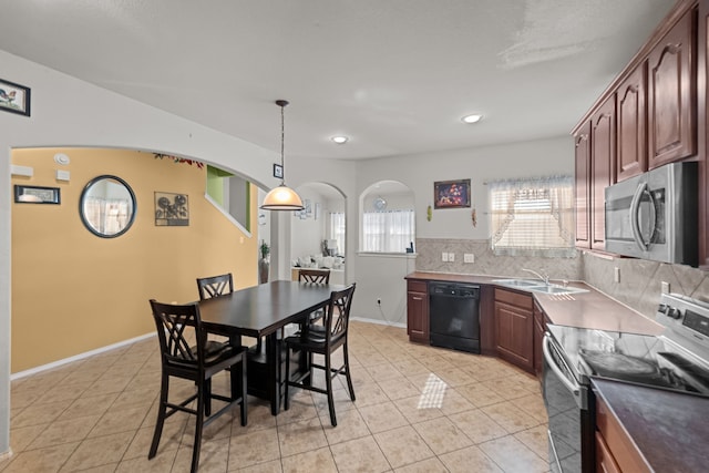 kitchen with a kitchen breakfast bar, stainless steel appliances, sink, decorative light fixtures, and tasteful backsplash