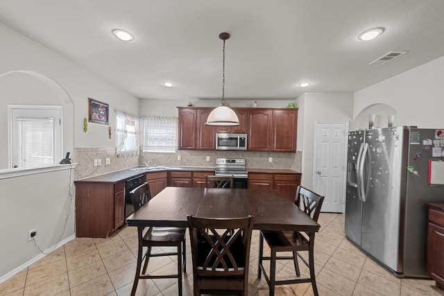 kitchen featuring sink, appliances with stainless steel finishes, pendant lighting, and tasteful backsplash