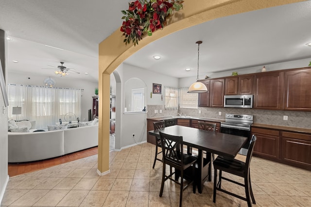 kitchen with ceiling fan, tasteful backsplash, appliances with stainless steel finishes, and hanging light fixtures