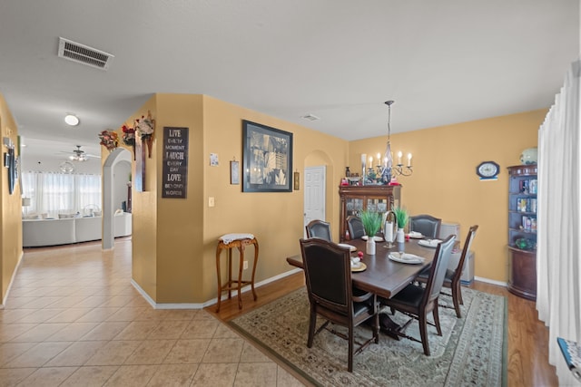 tiled dining space with ceiling fan with notable chandelier