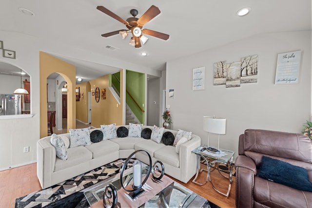 living room featuring light hardwood / wood-style floors, vaulted ceiling, and ceiling fan