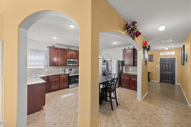 kitchen featuring light tile patterned floors, tasteful backsplash, appliances with stainless steel finishes, and sink