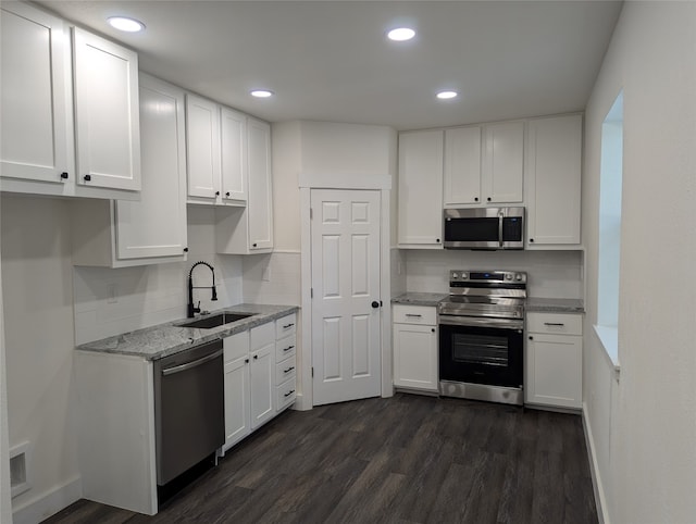 kitchen featuring light stone countertops, sink, stainless steel appliances, white cabinets, and dark wood-type flooring