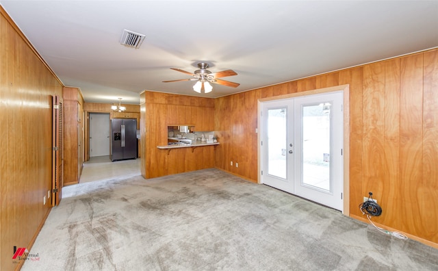 unfurnished living room with french doors, light carpet, and wooden walls