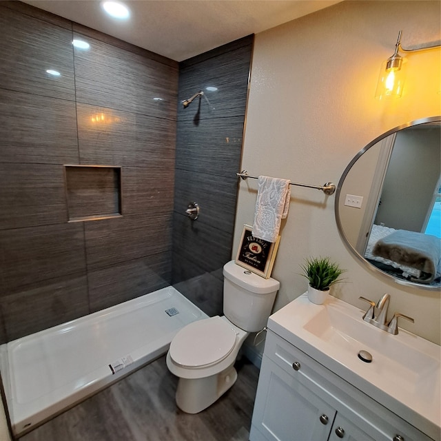 bathroom with vanity, a tile shower, wood-type flooring, and toilet