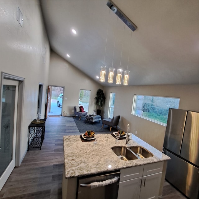 kitchen featuring hanging light fixtures, stainless steel appliances, a center island with sink, sink, and dark hardwood / wood-style flooring