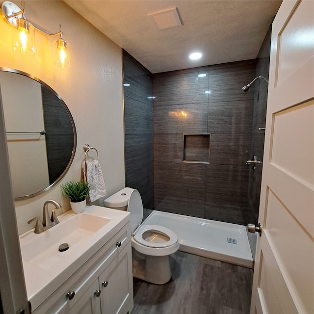 bathroom with vanity, tiled shower, hardwood / wood-style flooring, and toilet