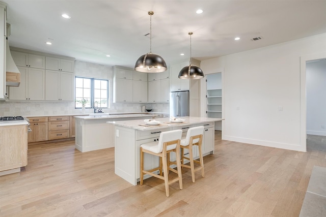 kitchen featuring high end fridge, a kitchen island, light wood-type flooring, and hanging light fixtures