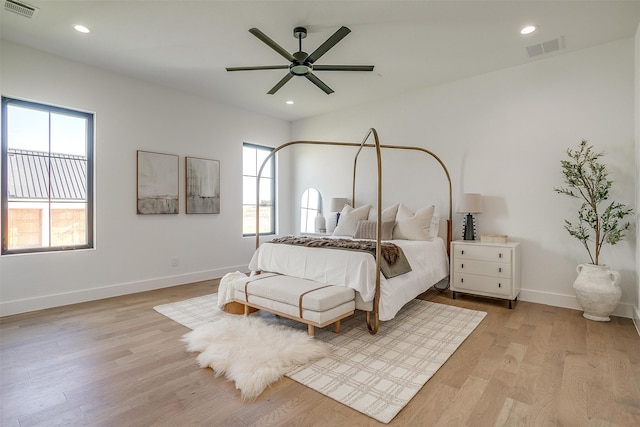 bedroom featuring ceiling fan, light hardwood / wood-style floors, and multiple windows