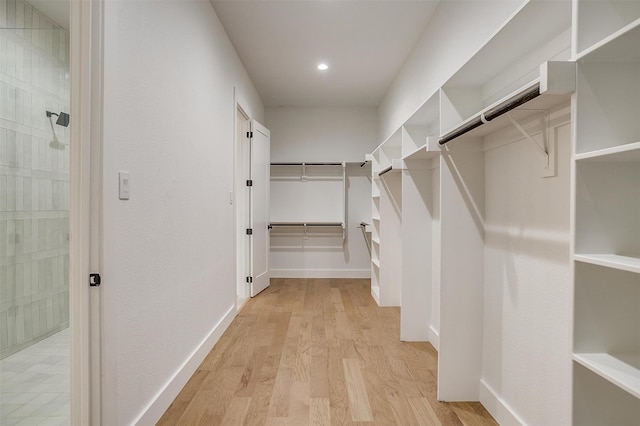 walk in closet with light hardwood / wood-style floors