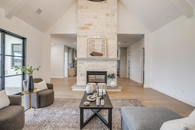 living room with light wood-type flooring, a fireplace, and high vaulted ceiling